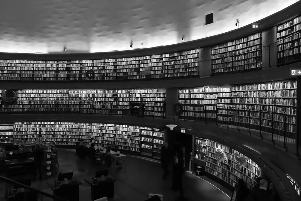 A large circular library hall has curved walls lined with tiers of bookshelves under a pale ceiling.