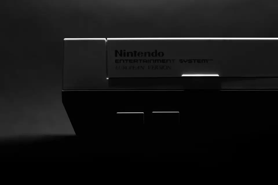 A dark close view of a gray Nintendo Entertainment System console shows its nameplate and front edge.