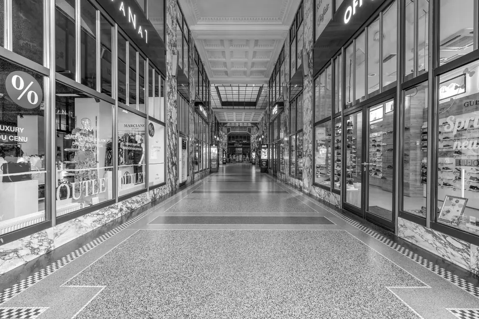A long, empty shopping arcade lined with glass storefronts under a glazed ceiling.