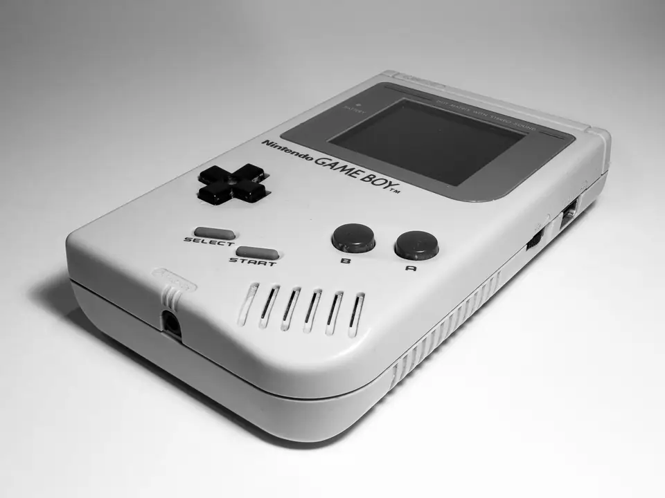 An original Nintendo Game Boy with a gray body, direction pad and two buttons rests on a white surface.