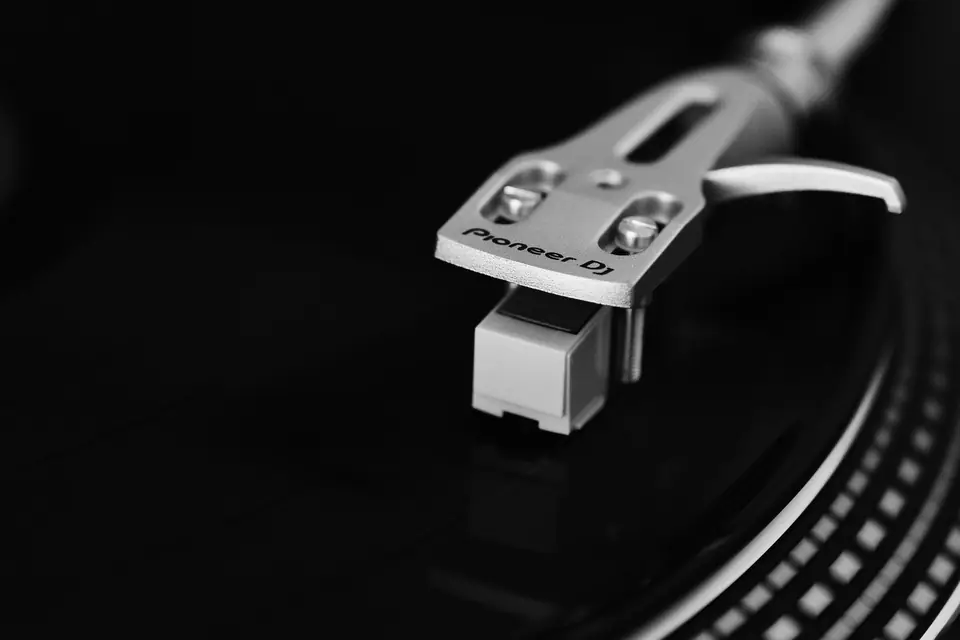 A turntable tonearm labeled Pioneer DJ hovers over a black vinyl record.