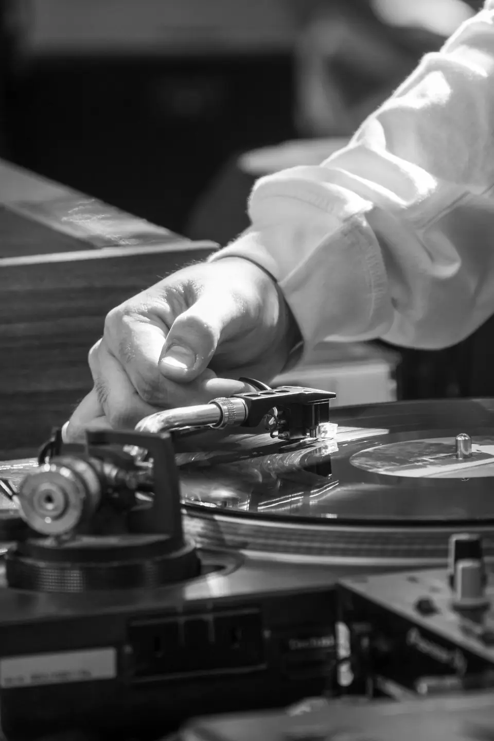 A person’s hand guides the tonearm of a turntable onto a spinning vinyl record.