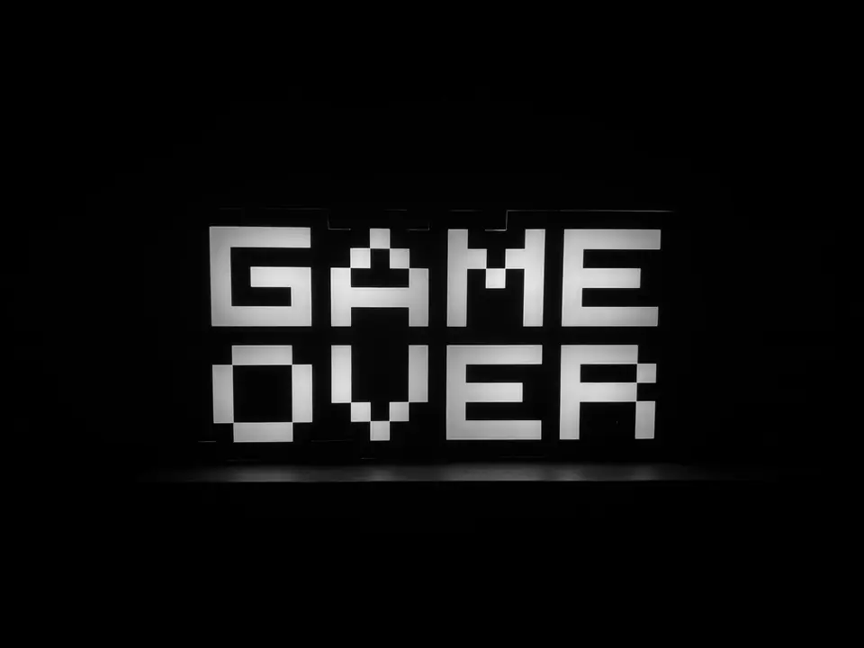 Blocky illuminated letters spell “GAME OVER” against a black background.