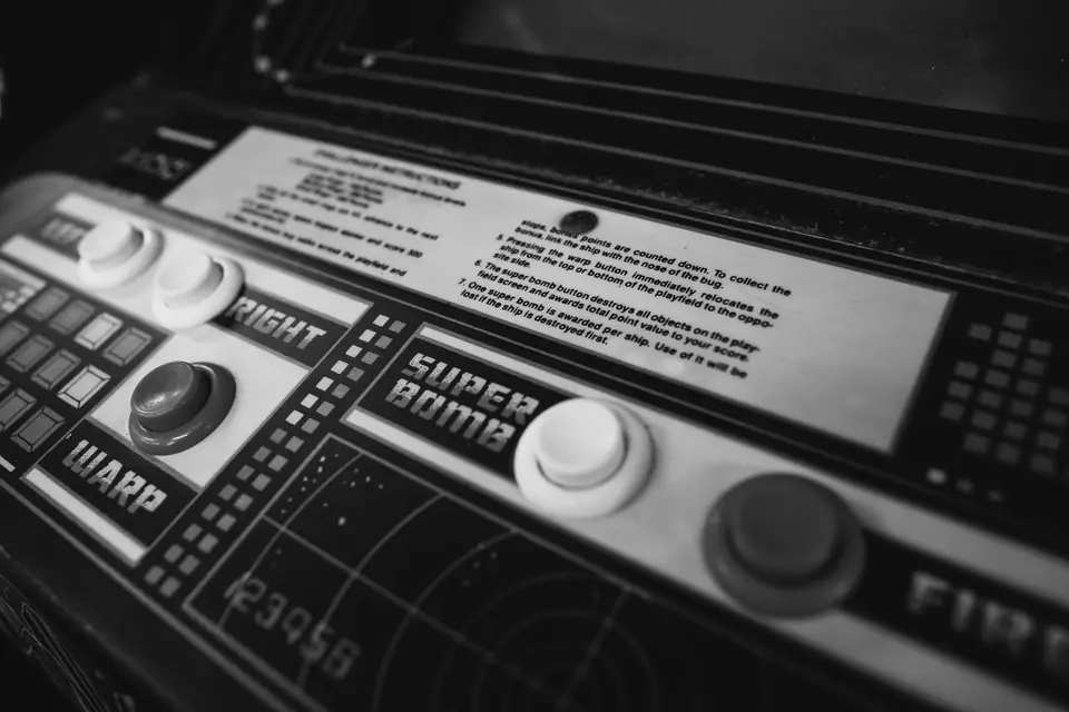 A close view of an arcade control panel shows labeled buttons, a joystick and a printed instruction card.