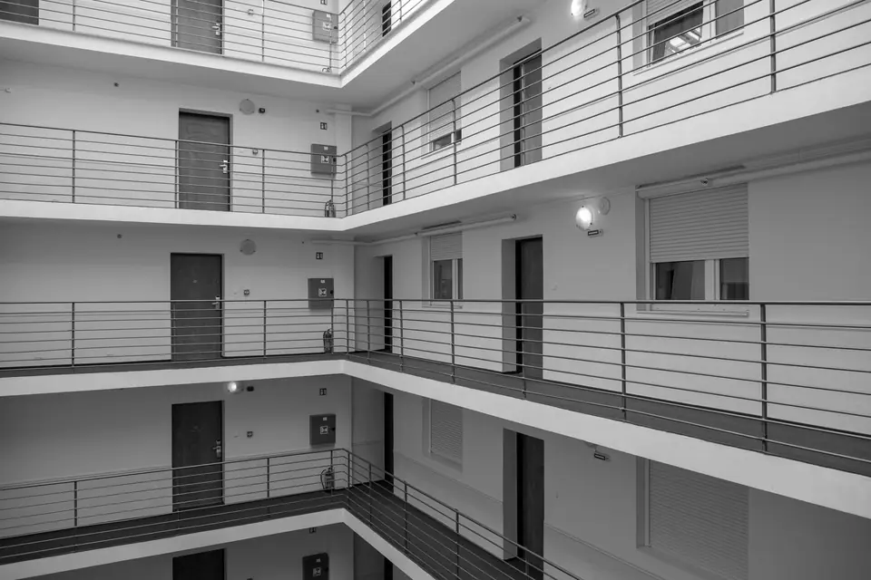 Three floors of an apartment building with identical doors along railed interior walkways.