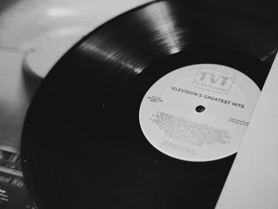 A vinyl record labeled “Television’s Greatest Hits” is partly pulled from its paper sleeve.