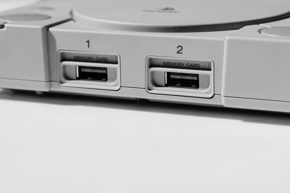 A close view of a gray console’s front panel shows two numbered memory card slots.
