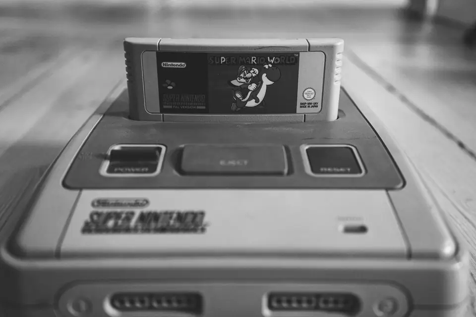 A game cartridge sits inserted in the top slot of a gray retro console.