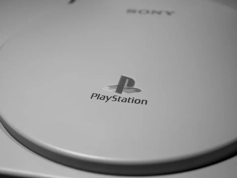 A close view of a gray console lid shows the PlayStation logo and wordmark.