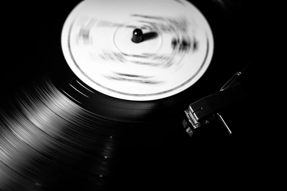 A vinyl record spins on a turntable with its label blurred by motion and the stylus resting in the groove.