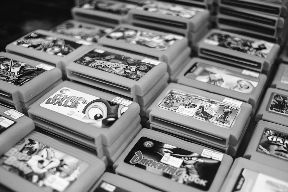 Stacks of retro game cartridges with colorful labels are piled closely together on a table.