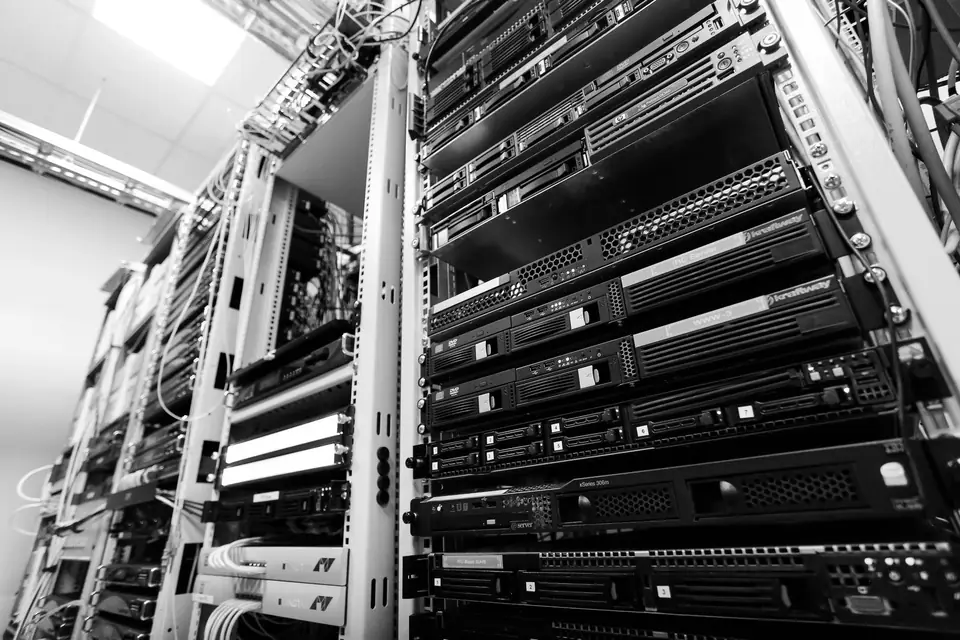 Tall server racks packed with equipment and cables stand in a bright data center aisle.