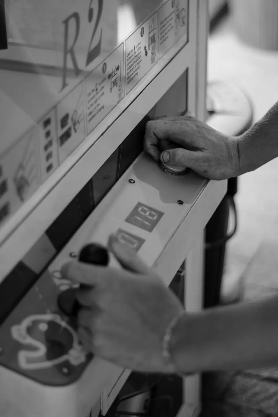 A person’s hands operate a joystick and a knob on a worn arcade control panel.