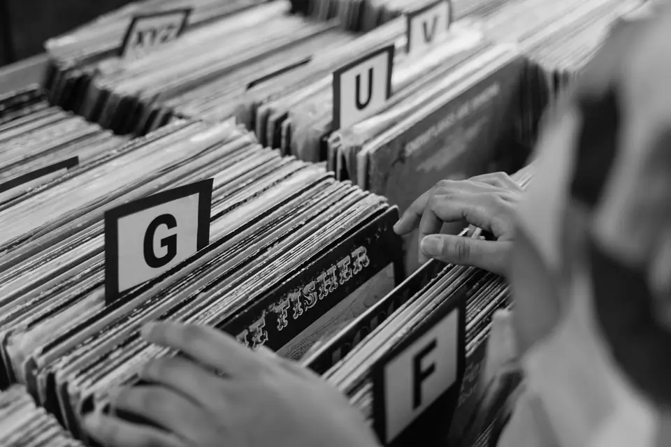 Hands flip through vinyl records in bins separated by letter dividers reading G, F, U and V.