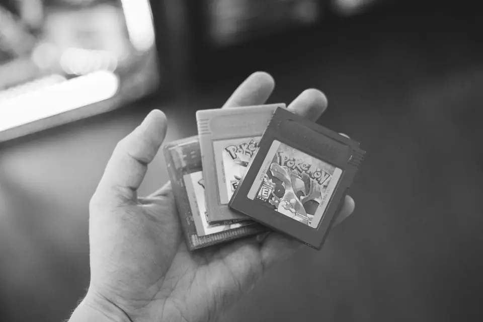An open hand holds three small handheld game cartridges with printed labels.