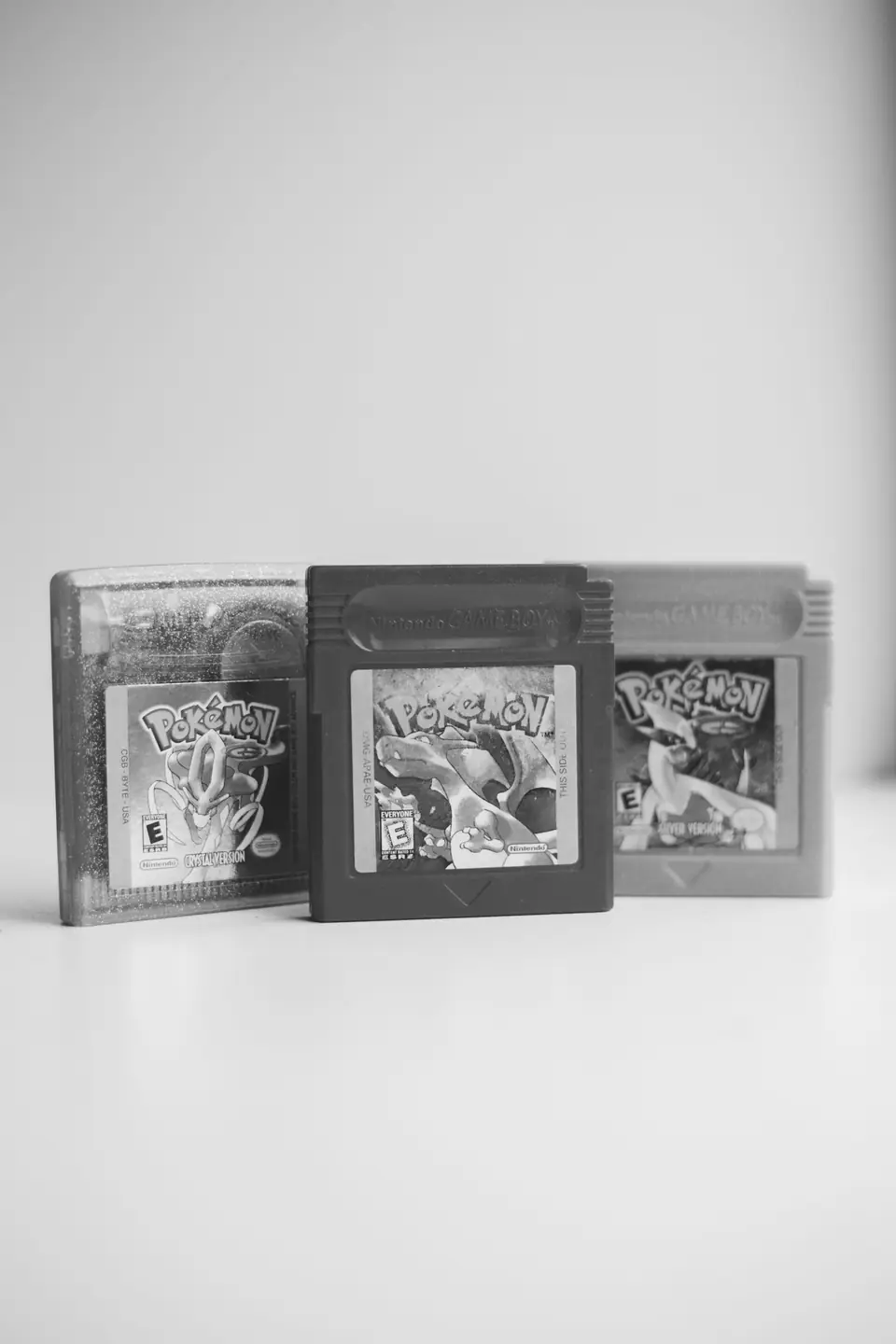 Three small handheld game cartridges with colorful labels stand upright on a white surface.