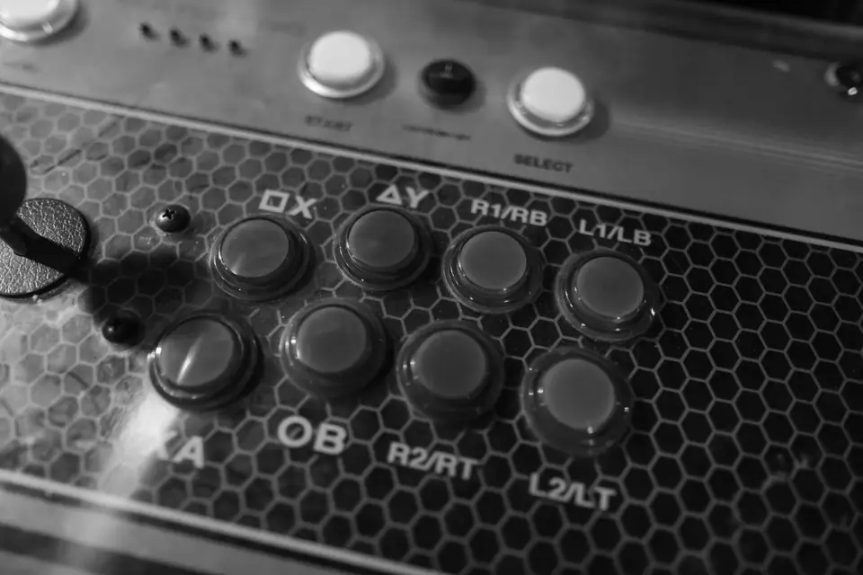 A close view of an arcade stick panel with labeled round buttons and a joystick.
