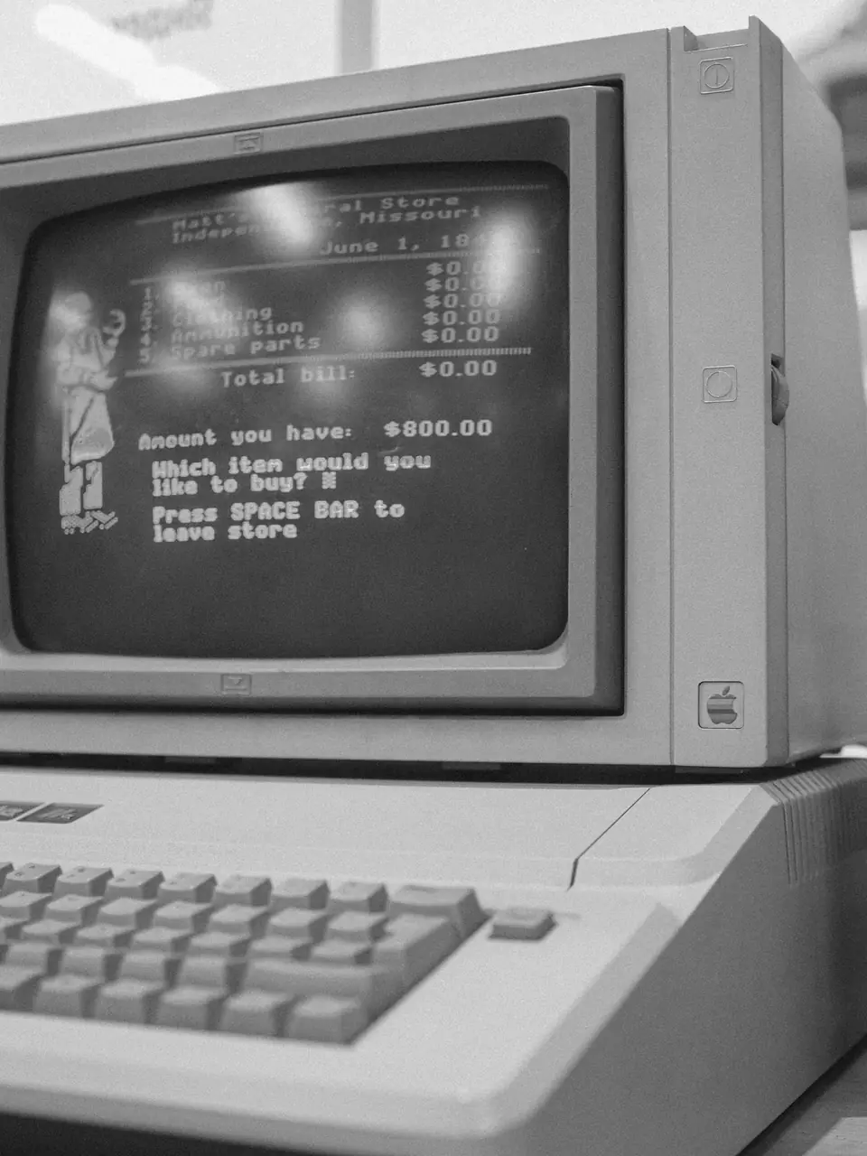 A vintage computer monitor displays a text-based game store menu above a beige keyboard.