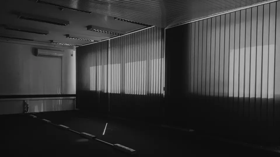 A dim, empty covered parking area with corrugated walls and light falling across the floor.
